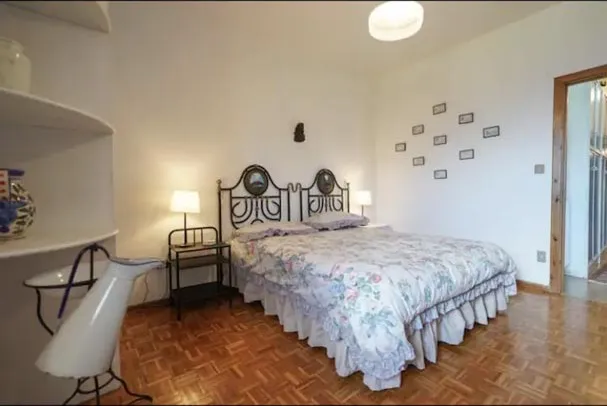 Double bedroom with a wrought-iron headboard, bedside tables, parquet floor and a floor lamp