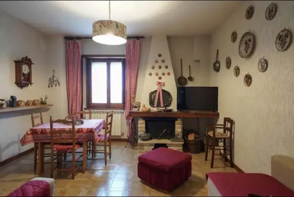 Dining table for six next to the fireplace, with red pouffes and decorative plates on the walls