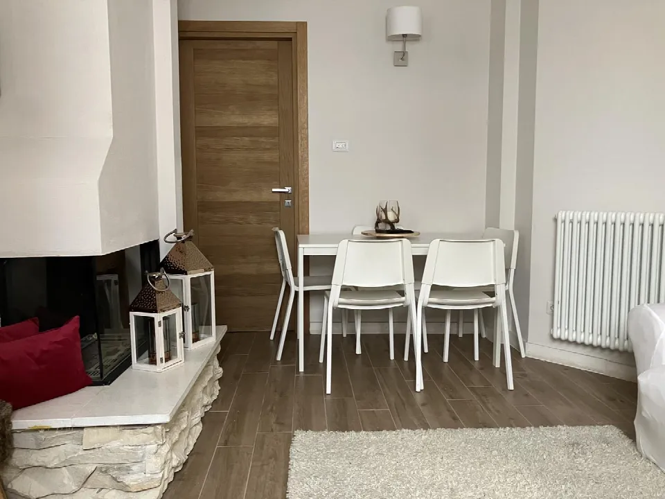 Living area with a modern white stone fireplace, lanterns and a white dining table